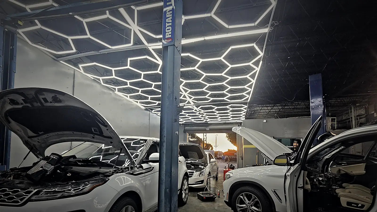 Range Rover and BMW being serviced under the Prestige hexagon-light ceiling in Oakland Park